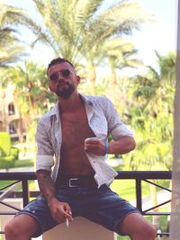 Young man wearing sunglasses sitting outdoors