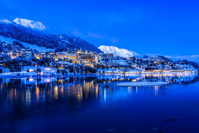 View of beautiful saint moritz city across from the lake at night with snow mountains