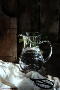 Close-up of jug with scissor and cloth on table