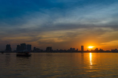 Scenic view of sea by buildings against sky during sunset