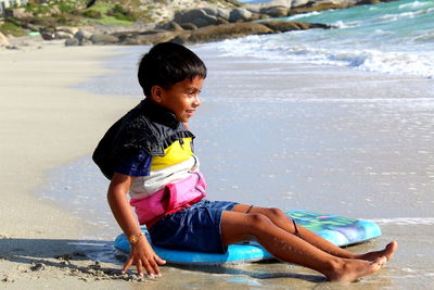 Full length of boy sitting at beach