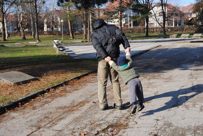 Rear view of man sitting on footpath in park