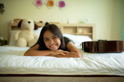 Portrait of smiling teenage girl relaxing on bed at home