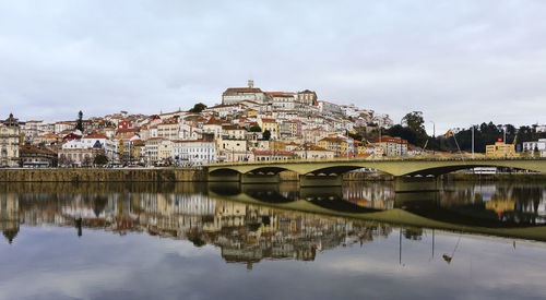 Reflection of buildings on river against sky in city