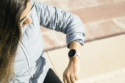 Latin woman with long hair looking at smartwatch