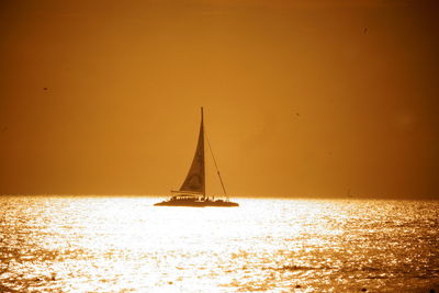 Sailboat sailing on sea against sky during sunset