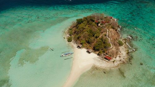 Tropical island and sand beach, turquoise water and coral reef. tourist boats on tropical island.