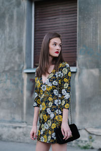 Young woman standing against building