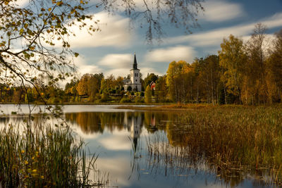 Reflection of trees in lake against cloudy sky