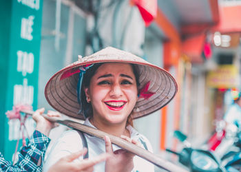 Close-up portrait of smiling woman in asian style conical hat