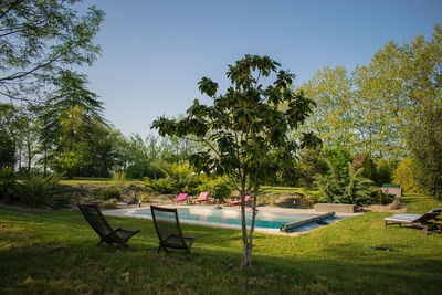 Chairs and table by swimming pool against sky