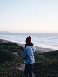 Rear view of man looking at sea against clear sky