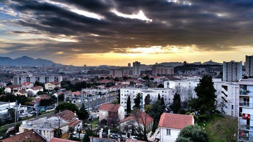 Cityscape against cloudy sky at sunset