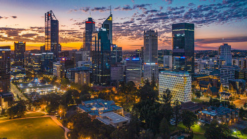 Illuminated buildings in city during sunset