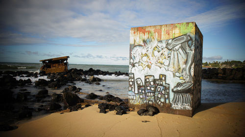 Graffiti on beach against sky