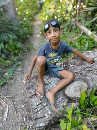 Full length of boy sitting in forest