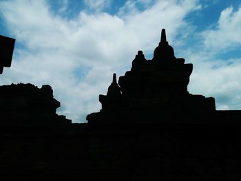 Silhouette of temple against cloudy sky