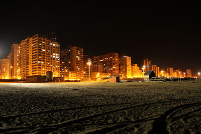 Illuminated city buildings against clear sky at night