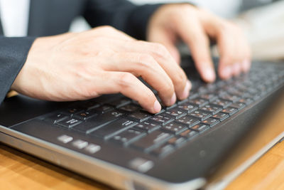 Midsection of person using laptop on table