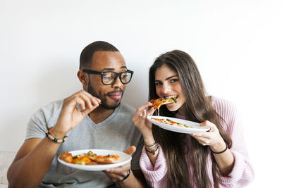 Young couple at home eating pizza