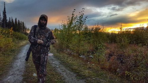 Man on field against sky during sunset