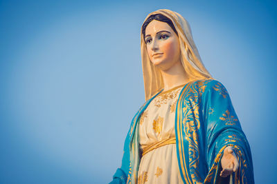 Portrait of woman standing against blue sky