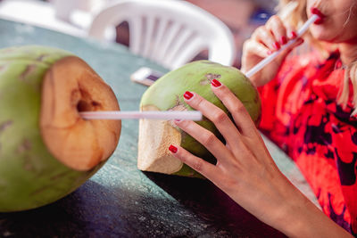 Close-up of young woman having coconut water at table