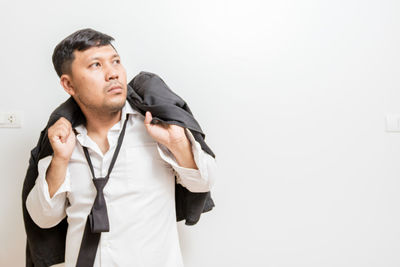 Man looking away while standing against white background