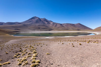 Scenic view of arid landscape against clear blue sky