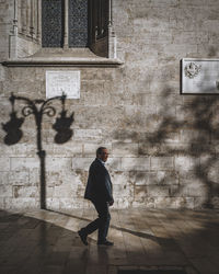 Side view of man walking on street against building