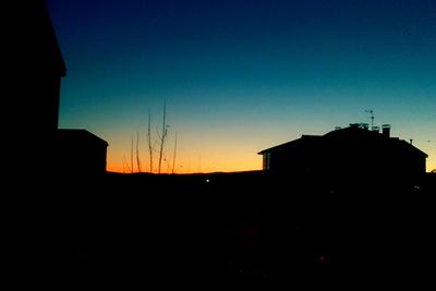 Low angle view of silhouette buildings against clear sky