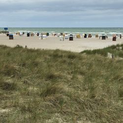 Hooded beach chairs on shore against sky