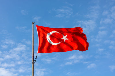 Low angle view of red flag against blue sky