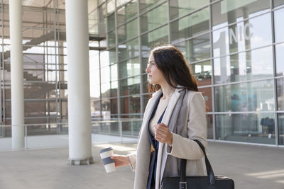 Side view of young woman using mobile phone in city