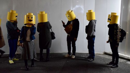 Panoramic view of people standing against yellow wall