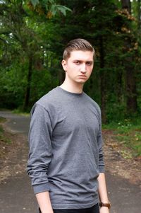 Portrait of young man standing against trees