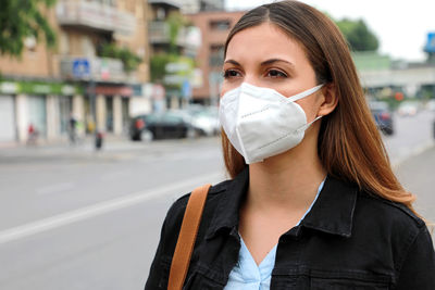 Woman in mask looking away while standing in city