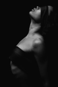 Side view of sensuous woman with ribbons against black background