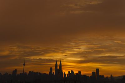 Silhouette of cityscape against orange sky during sunset