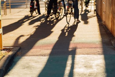 Low section of people riding bicycles on street during sunny day