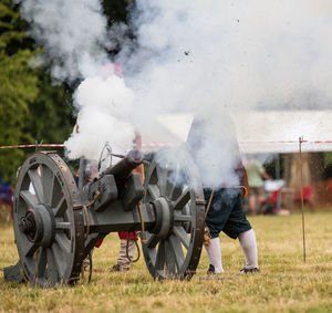 Man with cannon emitting smoke on field