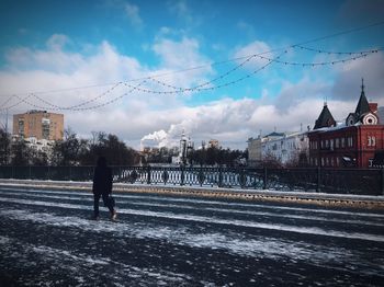 Rear view of man standing by buildings against sky