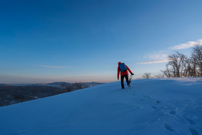 Rear view of person standing on snow against sky