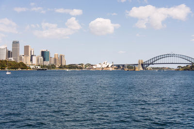 Bridge over sea by buildings against sky in city