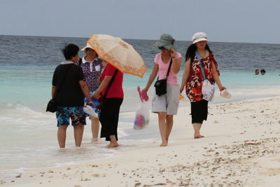 Rear view of people walking on beach