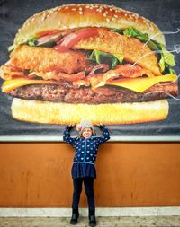 Optical illusion of girl lifting large hamburger on poster