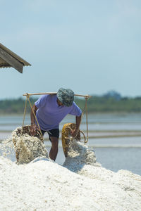 Rear view of man holding umbrella at beach against clear sky