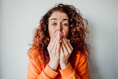 Portrait of woman sneezing while standing against wall