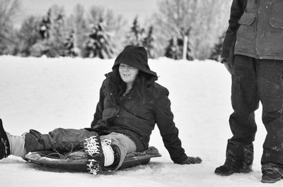 Young woman sitting snow covered land 