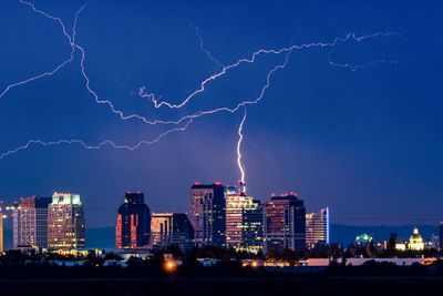 Lightning in city against sky at night